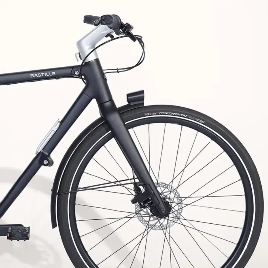 Vélo à cadre noir mat, gros plan sur la roue avant et le guidon.