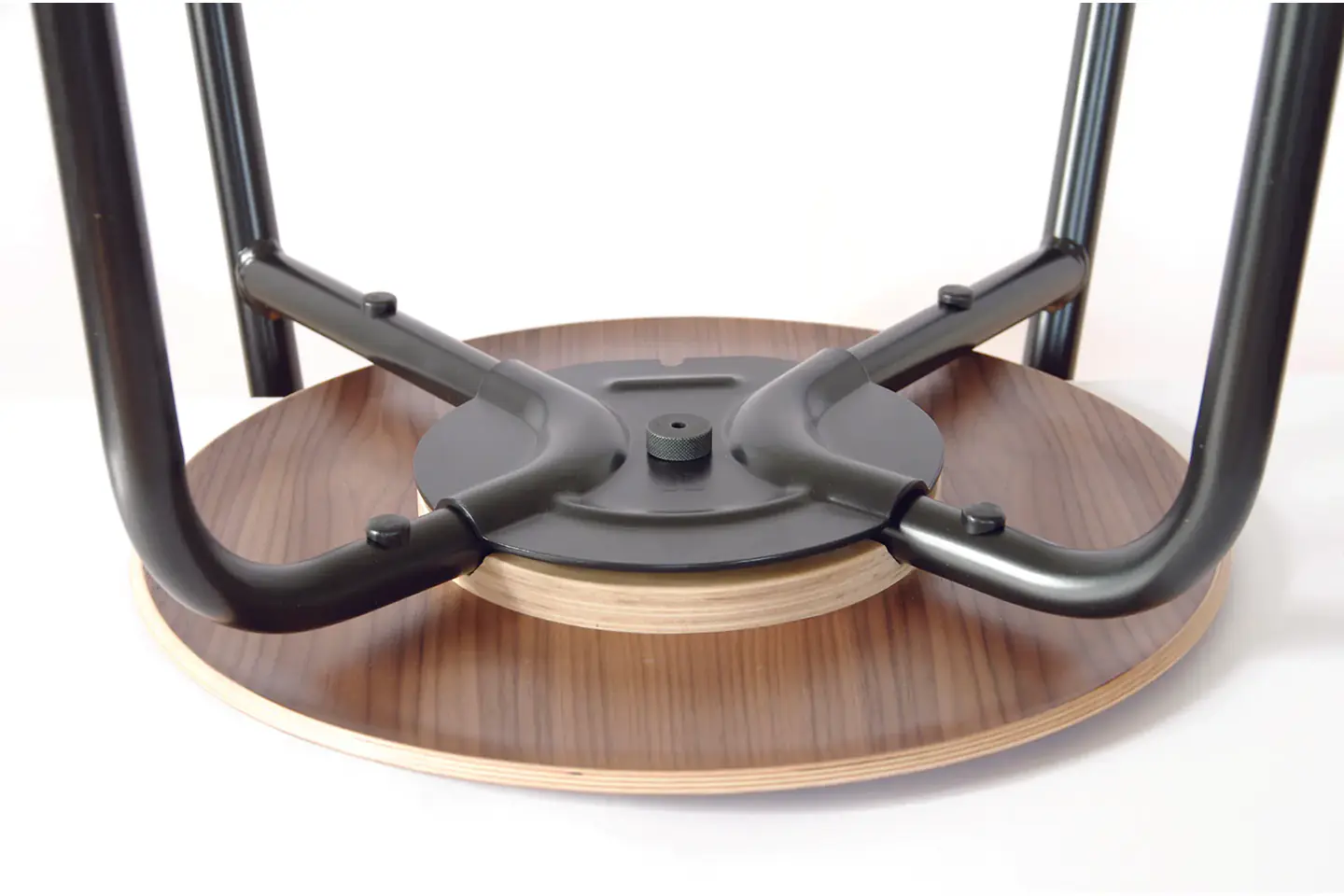 Gros plan sur le dessous d'une chaise en bois et sa fixation métallique.